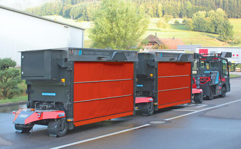 Fully automated and autonomous Factory Train outdoor tugger train from Neumaier Industry with telescopic fork load carrier for the automated pick-up and delivery of load carriers to/from transfer stations or directly to/from the ground